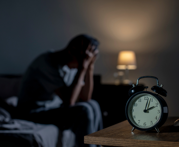 A man sittin on the bed with his head in his hands